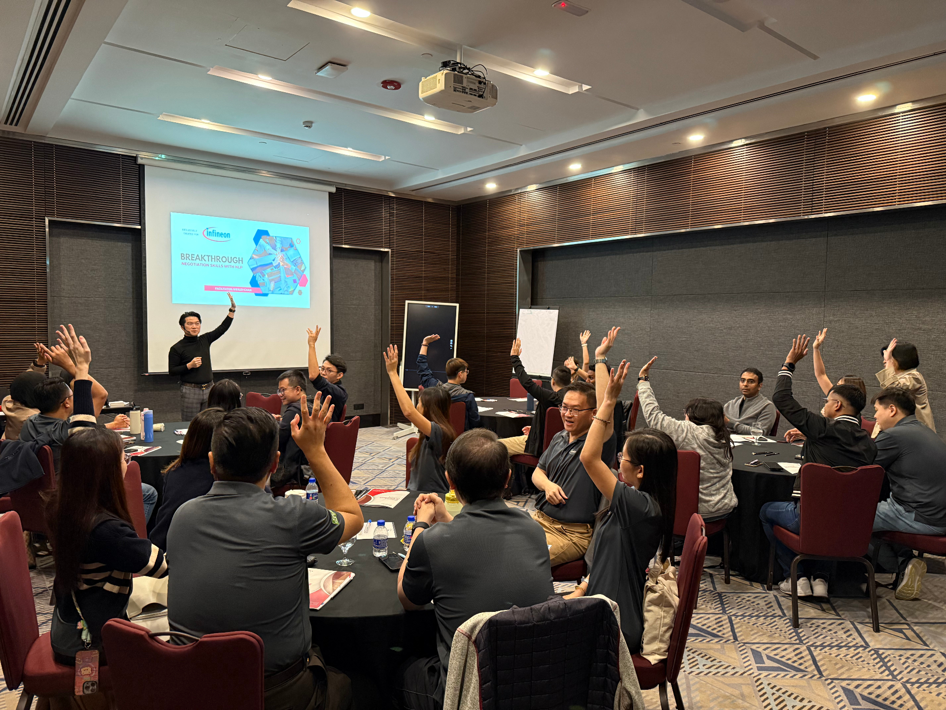 Wesley Chan facilitating a breakthrough negotiation skills development series with hands raised in engagement